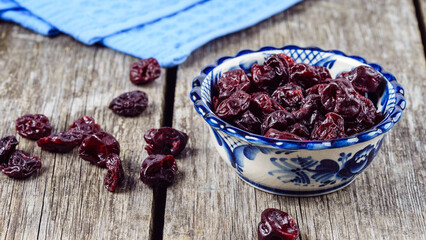 Dried cherries in a blue plate on a wooden table in a rustic style