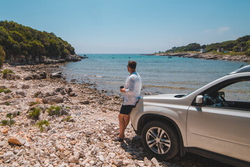 man near white suv car at summer sea beach