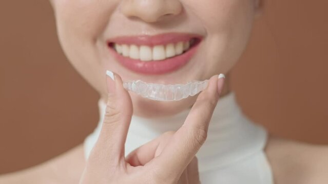 A young woman with beautiful teeth is holding Invisalign, healthy dental concept