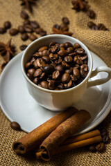 Coffee cup full of coffee beans. Roasted coffee beans on burlap.