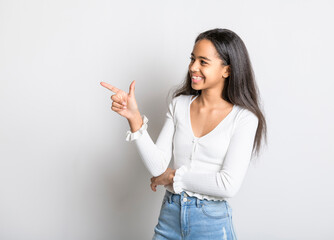 Beautiful black teen posing on studio white background pointing something