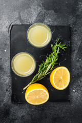 Traditional italian lemon alcohol drink liqueur limoncello with lemon and rosemary. Black...