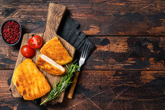 Crispy Cordon Blue Chicken fillet roll with ham and cheese served  on a wooden board. Wooden background. Top view. Copy space