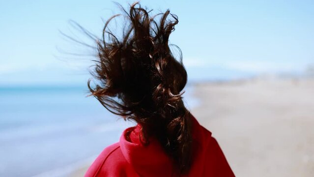 4K slow motion Young woman in red sweatshirt running on the beach. Sunny and windy day.