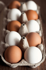 Closeup of mixed natural and organic chicken eggs brown and white in craft box on wooden table