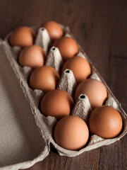 Top view natural and organic chicken eggs in craft paper box on brown wooden table