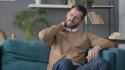 Man having Neck Pain while Sitting on Sofa 