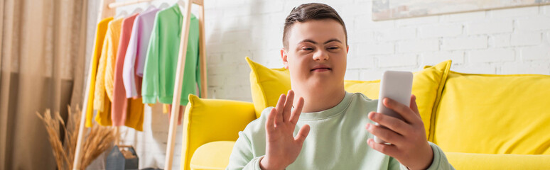 Teenager with down syndrome having video call on cellphone at home, banner.