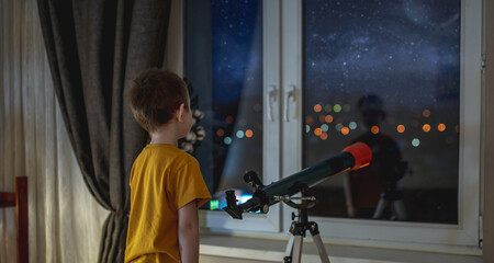 Cute boy is looking through a telescope at the night starry sky. Children's passion for space exploration