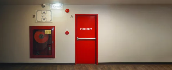 Tuinposter Fire exit door. Fire exit emergency door red color metal material with alarm and emergency light and fire extinguish equipment on building wall for safety protection. Doors for escape conflagration. © gnepphoto