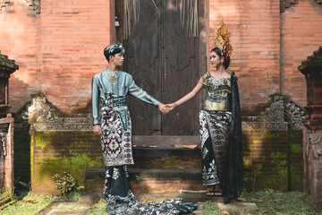 Bali teens girl and boy together holding hands in old Hindu temple.