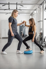 Fototapeta na wymiar Rehabilitation specialist helping little girl to do exercises at gym. Concept of physical therapy for back health and correct posture for kids