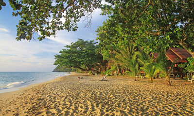 Ko Chang, Thailand - December 7. 2018: View on tropical white sand beach with green trees and wood bamboo houses