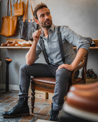 Male model in gray vintage clothing sitting an a chair posing