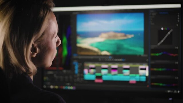 An experienced video production engineer works on a PC. A woman is doing color grading for a video. Professional