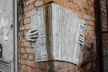 accordion sculpture on brick wall