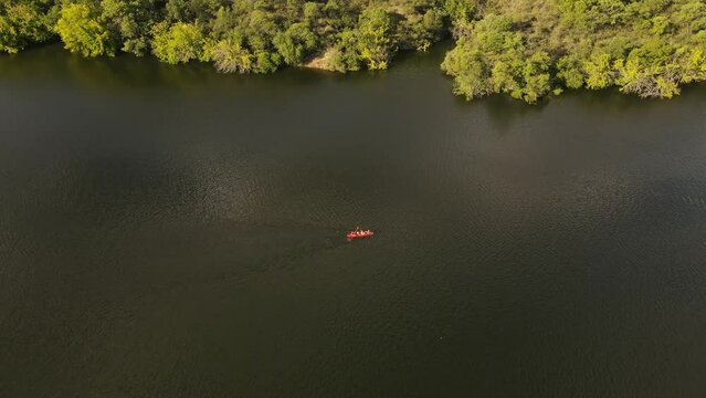Aerial top down of group of people in red kayak rowing over natural river in Argentina