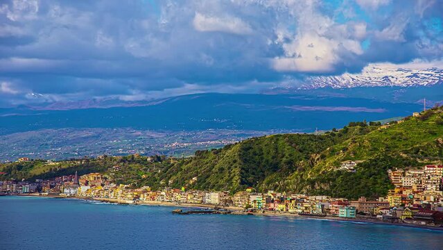 Static view of the seaside town of Mesina, Sicily, Italy with the view of etna volcano in the background on a cloudy day in timelapse.