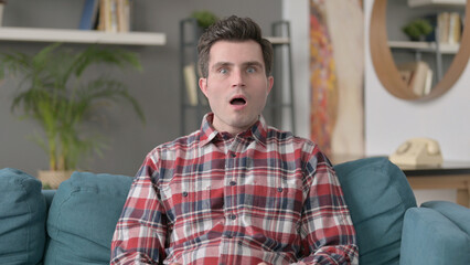 Fototapeta premium Portrait of Man Reacting to Failure while Sitting on Sofa 