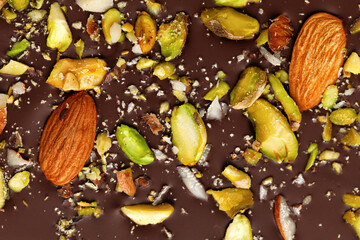Chocolate bar with almond and pistachios close up. Top view, macro.
