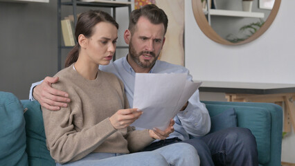 Obraz premium Couple having Failure while Reading Documents on Sofa 
