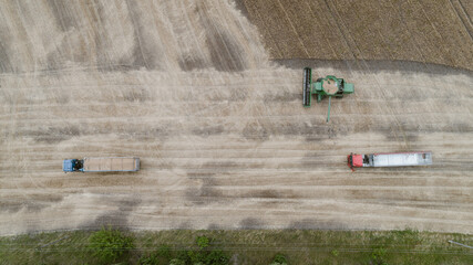 Fototapeta na wymiar Aerial view with harvester dumping crop into a truck trailer