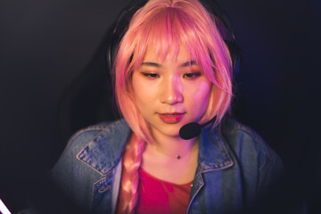Asian woman with pink braid wearing Jean jacket talking into the microphone. High quality photo