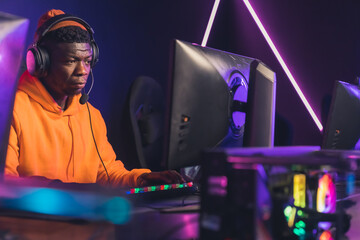 professional African American gamer focused on winning in online video games tournament medium closeup game battles neon light indoors. High quality photo