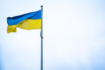 Flag of Ukraine on white sky background. National symbol of freedom and independence. Ukrainian flag waving in wind. Empty copy space.