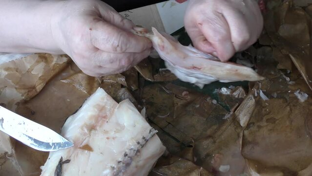 the cook cuts raw cod fish into pieces