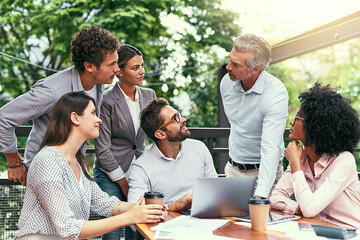 Nothing makes the dream work like teamwork. Shot of a team of colleagues using a laptop together during a meeting outdoors.