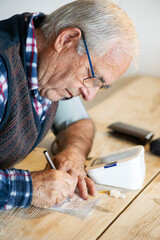 Hombre mayor controlando la tensión y anotando resultados