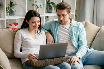 Young couple enjoy Social teleconferencing with their family via laptop screen in condominium...