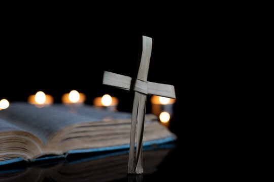 cross made from palm leaf with bible and candles 
