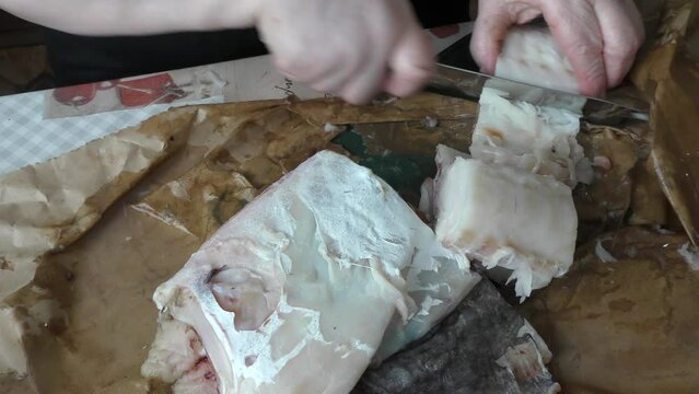 the cook cuts raw cod fish into pieces