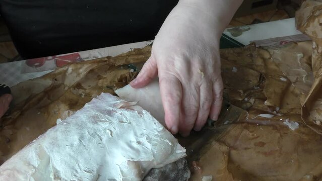 the cook cuts raw cod fish into pieces