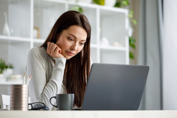 Portrait of a brunette woman working in an office with a laptop computer. A woman with a laptop looks into the camera and smiles sweetly.