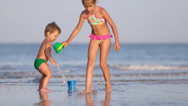 Older sister playing with younger brother aground near the shore on summer vacation