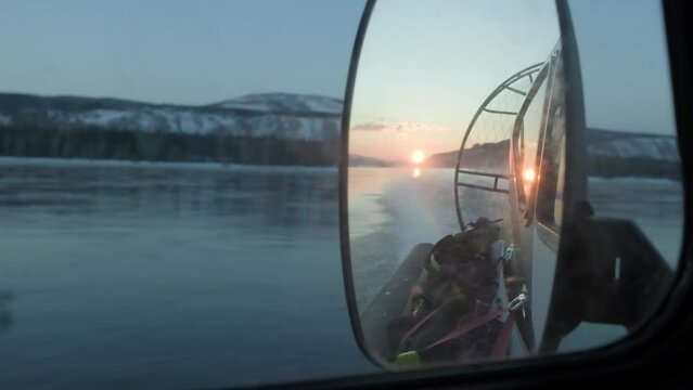 Close-up mirror of a hovercraft traveling on a river in winter
