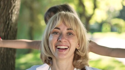 Close-up portrait of excited woman laughing as little girl covering eyes with hands. Happy Caucasian mother smiling having fun with pretty daughter in summer spring park on weekend