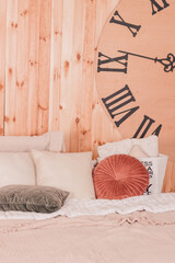 Pillows lie on a soft bed against the background of a wall clock