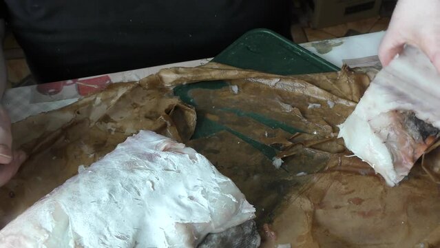 the cook cuts raw cod fish into pieces