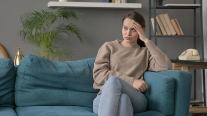 Woman having Headache while Sitting on Sofa 