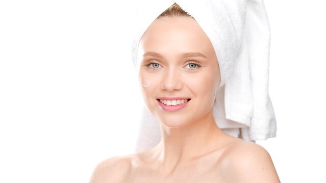 Young European fit woman with towel on her hair smiling wide for the camera on white background | Moisturizer advertising concept
