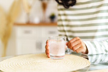 Dissolving fizz drug in glass of water. Unrecognizable female taking medicine at home