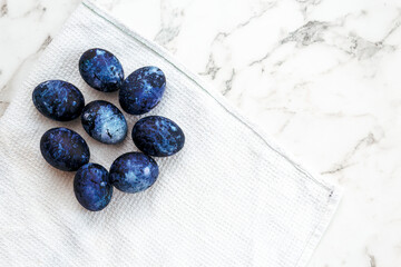 Cosmic colored eggs lie on a white waffle towel on a marble table. Easter eggs on the table