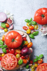 Flat lay composition of different tomatoes, onion, basil and garlic