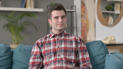 Portrait of Man Showing NO Sign while Sitting on Sofa 