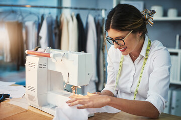Shes sewing it all together. Cropped shot of an attractive young fashion designer using a sewing...