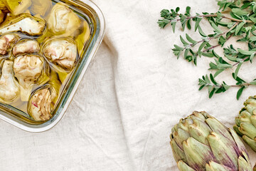Artichokes hearts marinated with olive oil and herbs. Pickled artichoke with garlic in glass bowl...